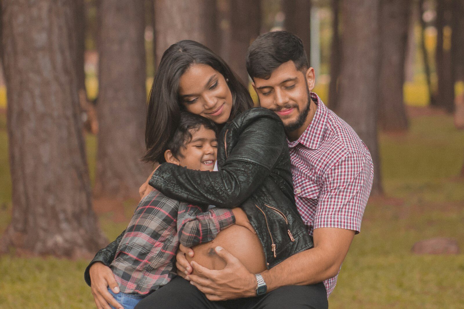 Casal abraçando o filho em um parque, transmitindo proteção familiar