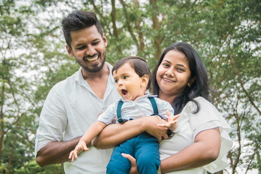 Casal sorridente segurando o filho pequeno ao ar livre